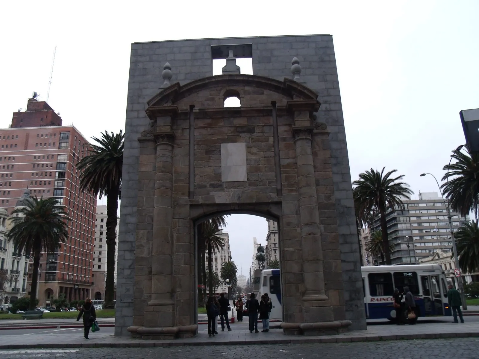 A Puerta de la Ciudadela, portal de pedra do século XVIII no centro de Montevidéu, com prédios e palmeiras ao redor