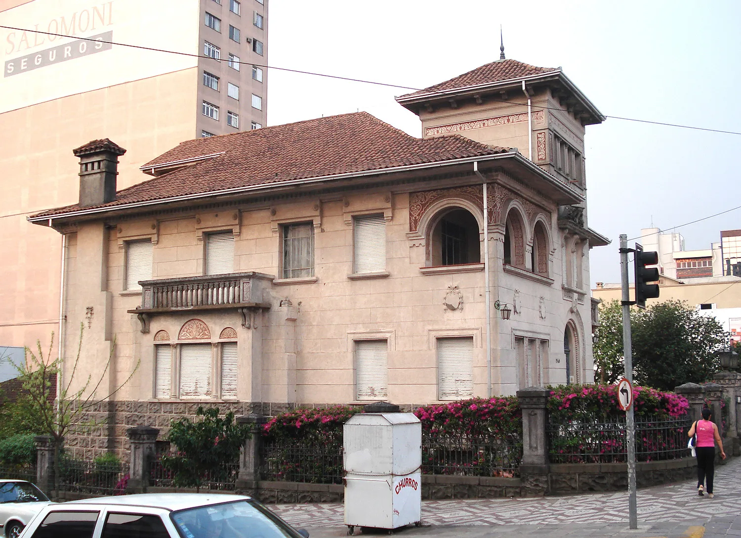 Casarão eclético de dois pavimentos com torre, telhado de cerâmica e ornamentos em relevo, hoje cercado por prédios modernos